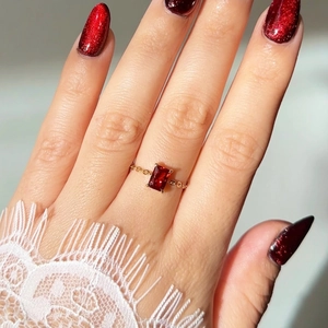 Detail of red emerald-cut zircon ring with 18K gold plated adjustable chain band