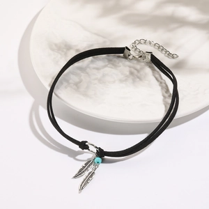 Detail of bohemian black cord choker featuring silver feather pendants and turquoise bead
