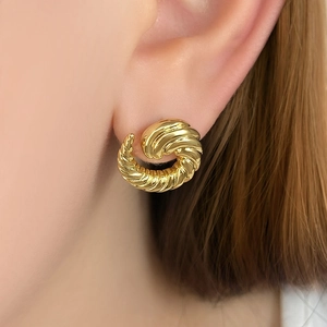 Detailed close-up of golden spiral twisted earrings worn, showcasing elegant metallic texture