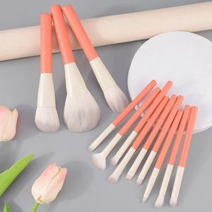 Professional 13-piece coral orange makeup brush set displayed on stylish elegant stands
