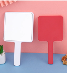 Square handheld makeup mirrors in white and red colors on a decorative studio background