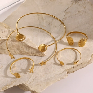 Gold starfish and shell pendant necklace and bracelet set on stone pedestal