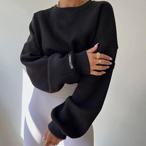 Close-up of white INSTUNNING embroidery on black oversized knit sweatshirt sleeve