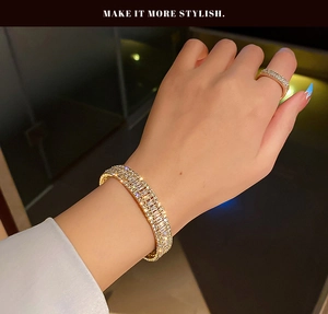 Détail macro de l'ensemble bracelet et bague dorés de luxe sertis de zircons