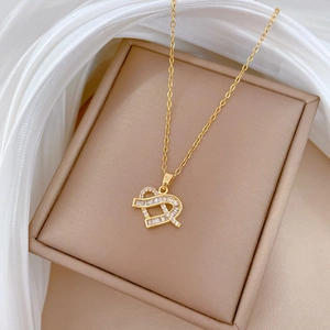 Close-up of a gold heart pendant necklace with shimmering cubic zirconia on beige silk fabric