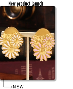 Detail of 18k gold daisy earrings featuring pink and white enamel petals on a gold stand