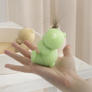 Close-up of textured bear candles in lime green and cream yellow on a marble base