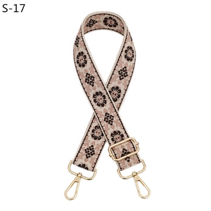 Close-up of ethnic floral jacquard bag strap with gold metal buckles and lobster clasps