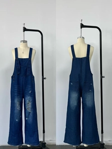 Detail view showing distressed denim texture and ripped holes on loose overalls