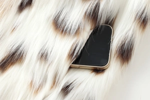 Detailed close-up of faux fur texture with brown spots and interior pocket utility