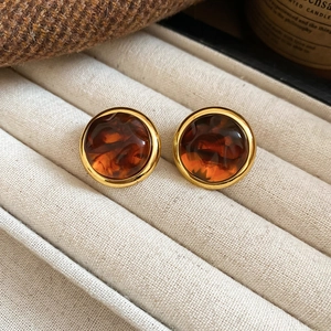Gros plan de boucles d'oreilles vintage ambrées avec bordure dorée sur plateau velours