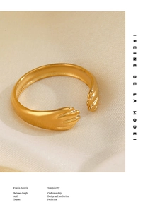 Détail d'une bague dorée ajustable mains enlacées sur fond de soie