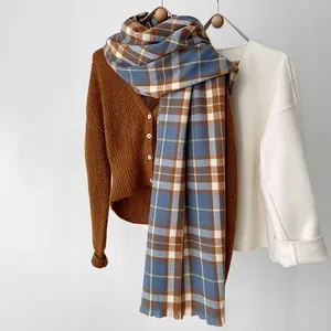 Detail of blue and brown checkered pattern scarf with soft cashmere texture and fringe edges