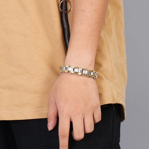 Detail of two-tone gold and silver stainless steel chain bracelet on a male wrist
