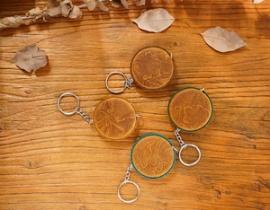 Detail view of round leather keychains with floral embossing on a rustic wooden desk
