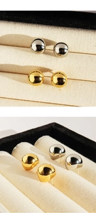 Polished gold and silver teardrop stud earrings displayed on a velvet jewelry box