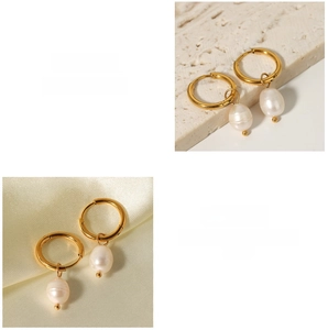 Detailed macro view of gold hoop earrings with natural freshwater pearl pendants