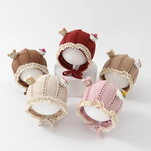 Detailed view of baby knit hats in five colors featuring lace edges and cute bear charms