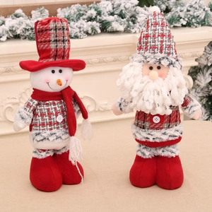 Christmas Santa Claus and snowman dolls in red plaid outfits on a cozy indoor mantle