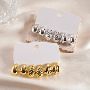 Détail de boucles d'oreilles en forme de goutte d'or et d'argent sur pierre et soie