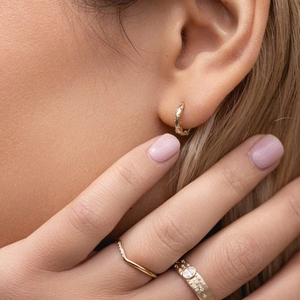Detailed close-up of golden S925 sterling silver hoop earrings and zircon-encrusted rings
