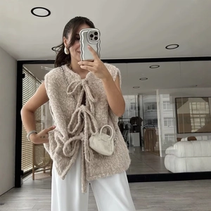 Beige plush vest with front bow ties and soft texture for a casual stylish women look