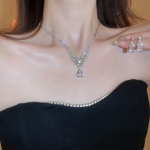 Close-up of elegant V-shaped rhinestone necklace and teardrop earrings set on model