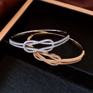 Détail macro de bracelets à nœuds entrelacés en plaqué or et argent avec cristaux pavés