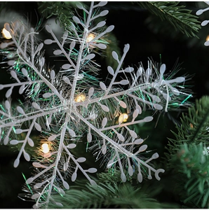 Close-up of white snowflake ornament with iridescent fibers on a Christmas tree branch