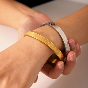 Detail of Roman numeral engraved bangles in gold and silver finish on a female wrist