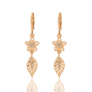 Detailed macro shot of champagne gold floral earrings with zircon stones and hollow leaves