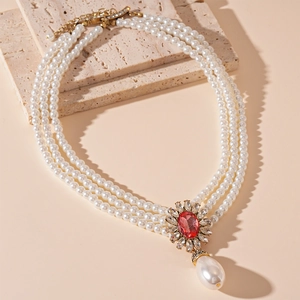 Detail of vintage three-layer pearl necklace with red stone and teardrop pendant