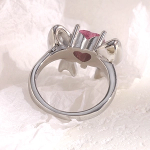Close-up of pink heart-shaped crystal ring with bow design in 18K gold plated steel