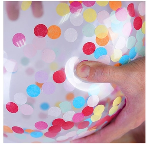 Close-up of a hand pressing a transparent balloon filled with colorful round confetti