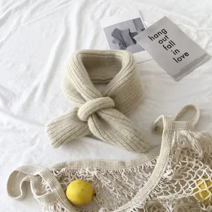 Close-up of soft beige knitted baby scarf with ribbed texture and cross-loop closure
