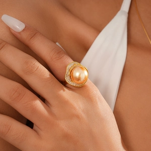 Close-up of golden ring with large champagne pearl and shimmering zircon halo