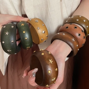 Détails de larges bracelets en bois avec rivets étoiles métalliques tons terre