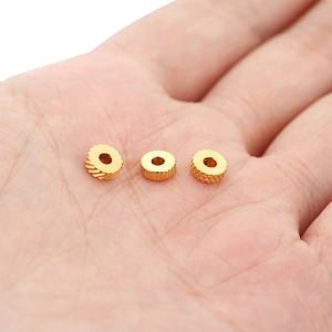 Close-up of three 6mm gold textured stainless steel spacer beads held in a hand