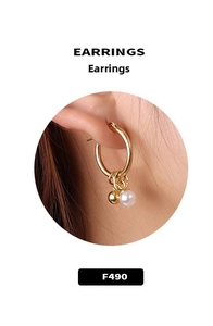Close-up of golden hoop earrings with white pearl and solid metal ball pendants