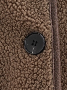 Close-up of brown fleece fabric with black leather trim and four-hole button detail