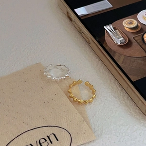 Detail of adjustable gold and silver heart-shaped rings with thorn textures on white fabric