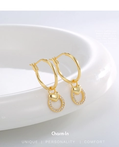 Detailed close-up of golden heart hoop earrings with cubic zirconia on white ceramic