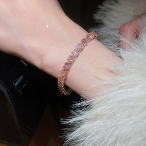 Close-up of pink square-cut zircon tennis bracelet in gold finish on female wrist
