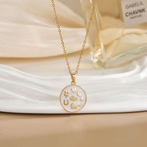 Golden necklace with circular heart and moon enamel pendant on soft fabric background