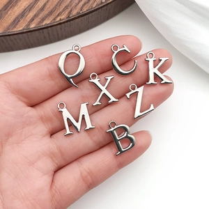Versilberte Buchstaben-Anhänger für DIY-Schmuck in der Hand auf weichem Hintergrund