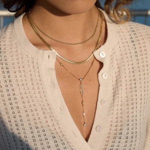 Close-up of triple layered gold plated necklace set with rhinestones on model wearing knitwear