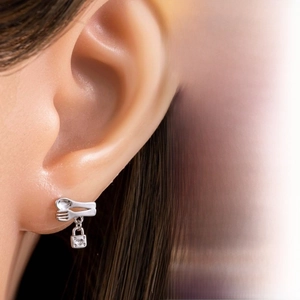 Macro shot of silver spoon and fork stud earring with a heart engraved lock pendant