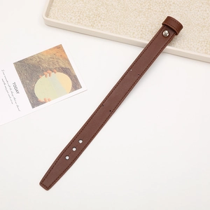 Detail view of a brown leather wrist strap with silver metal buckle and stitching