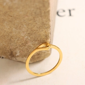 Minimalist gold-finish hollow teardrop ring displayed on a natural textured stone