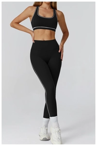 Detail view of high-waist black yoga leggings and sports bra with white piping accents